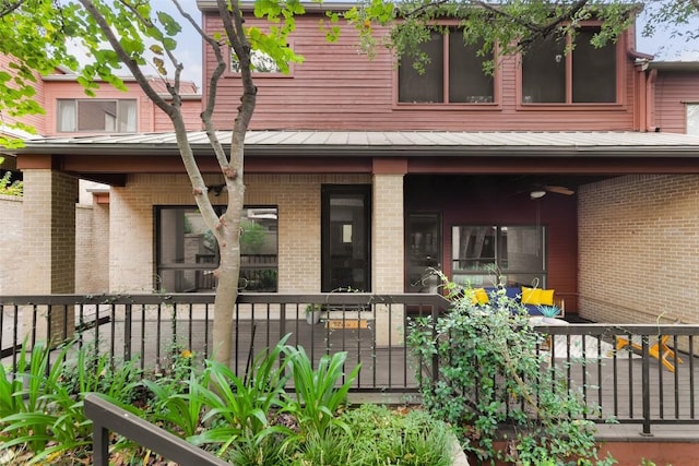 back of property featuring a standing seam roof, brick siding, metal roof, and fence