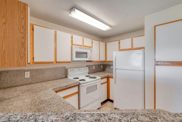 kitchen featuring light stone counters, light tile patterned floors, white appliances, and white cabinetry