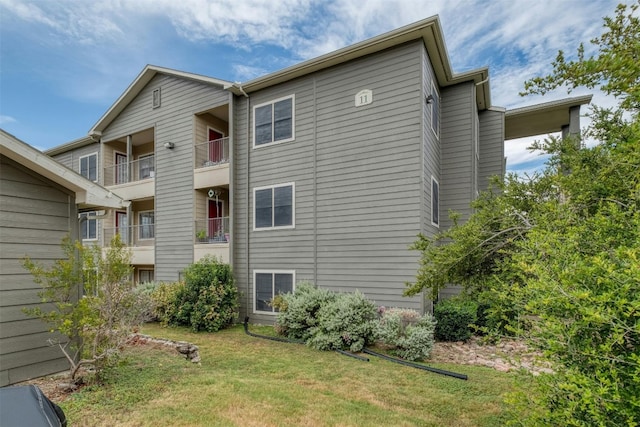 view of home's exterior with a lawn and a balcony