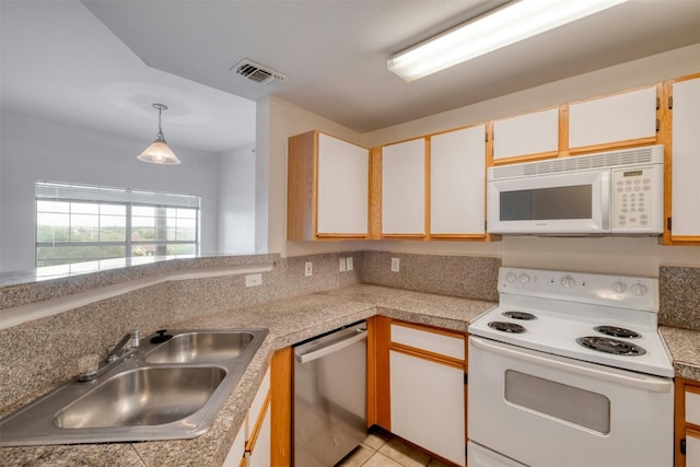 kitchen with light tile patterned floors, white appliances, sink, and white cabinets