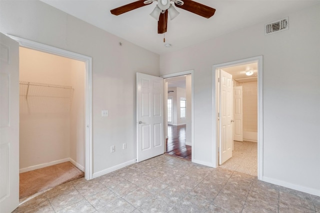 unfurnished bedroom with a walk in closet, ceiling fan, and a closet