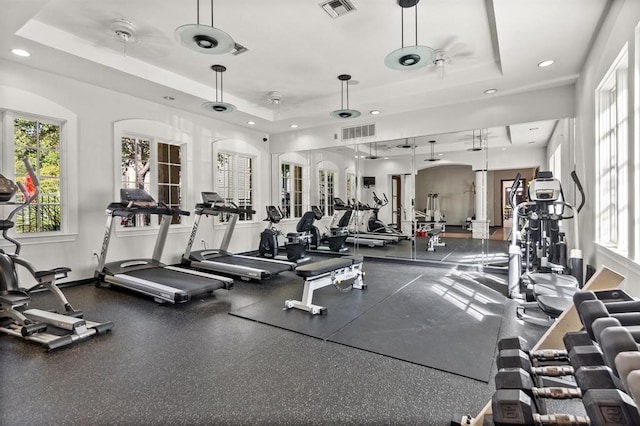 gym with ceiling fan and a tray ceiling