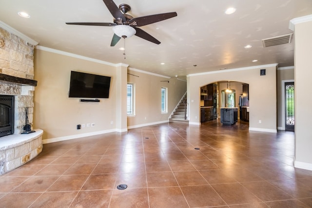 unfurnished living room with tile patterned flooring, ceiling fan, a fireplace, and ornamental molding