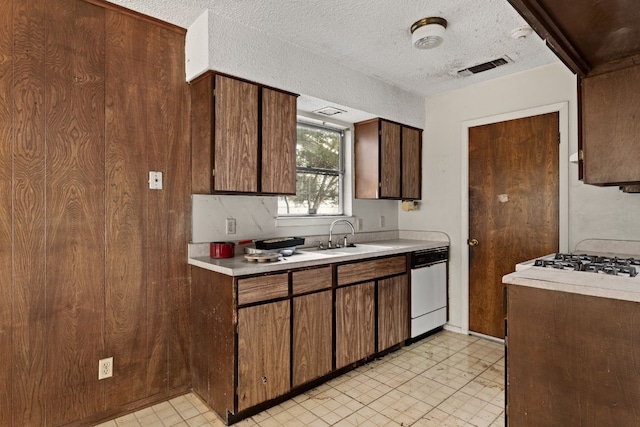 kitchen featuring white dishwasher, sink, and a textured ceiling