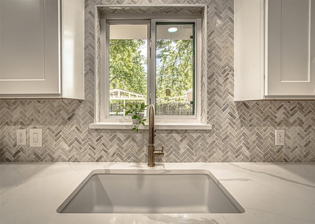 kitchen featuring light stone counters, sink, and white cabinets