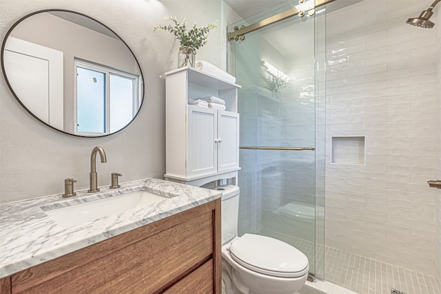 bathroom featuring an enclosed shower, toilet, and vanity