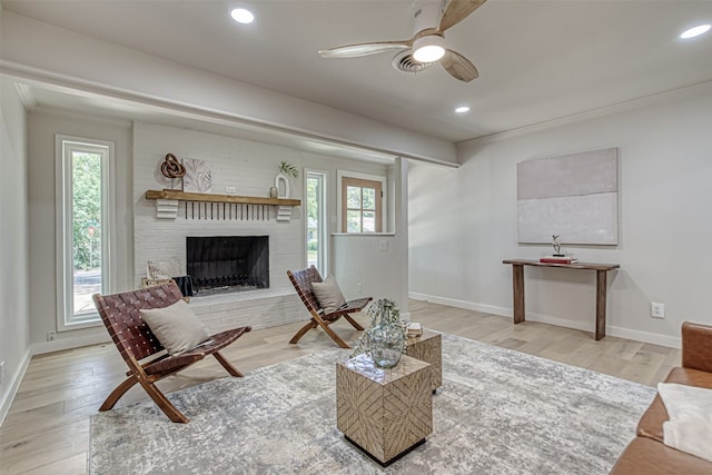 living room featuring a wealth of natural light, ceiling fan, and a brick fireplace