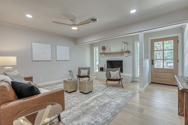 living room with a fireplace, ceiling fan, ornamental molding, and light hardwood / wood-style floors