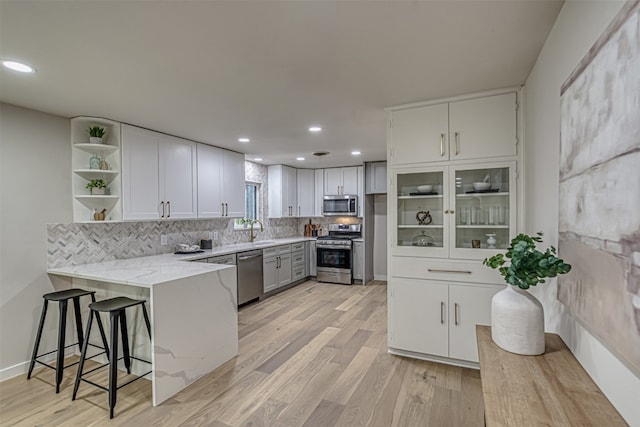 kitchen with white cabinetry, light hardwood / wood-style flooring, stainless steel appliances, kitchen peninsula, and sink