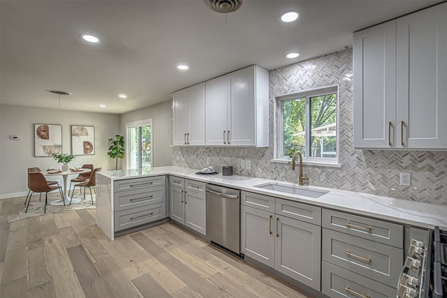 kitchen with plenty of natural light, stainless steel dishwasher, sink, and light hardwood / wood-style flooring