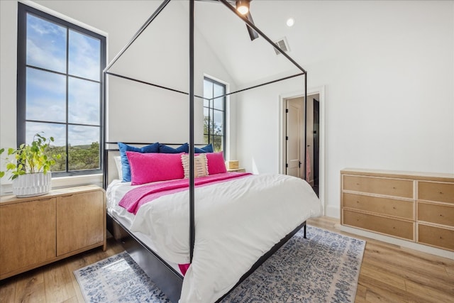 bedroom with high vaulted ceiling and light hardwood / wood-style flooring