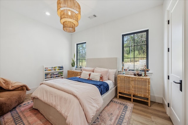 bedroom with a notable chandelier and light hardwood / wood-style floors