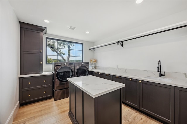 laundry area featuring cabinets, sink, washing machine and dryer, and light hardwood / wood-style flooring