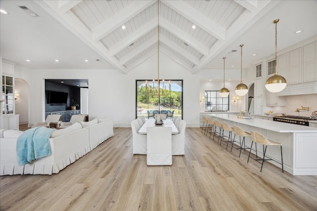 dining room featuring high vaulted ceiling, an inviting chandelier, beam ceiling, and light hardwood / wood-style flooring