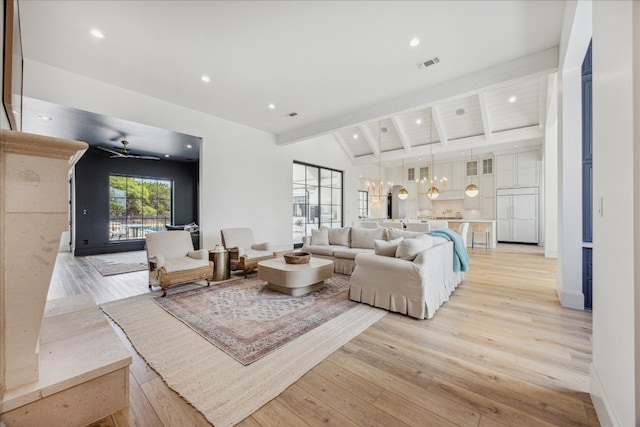 living room with lofted ceiling with beams, an inviting chandelier, and light hardwood / wood-style flooring