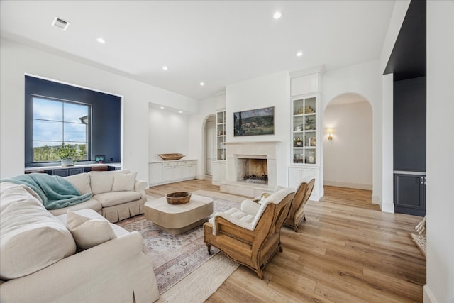 living room featuring built in shelves and light hardwood / wood-style floors