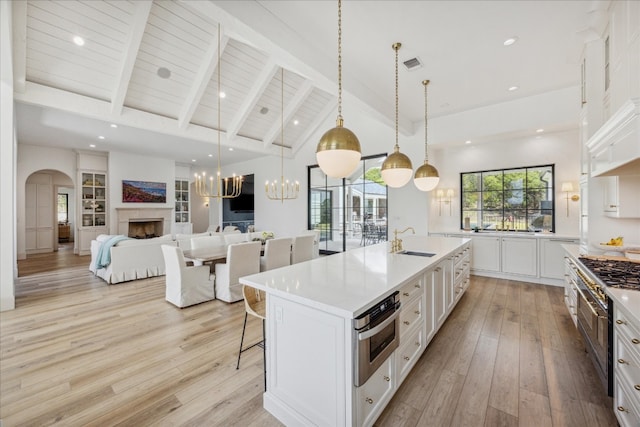 kitchen featuring white cabinetry, sink, an island with sink, and decorative light fixtures