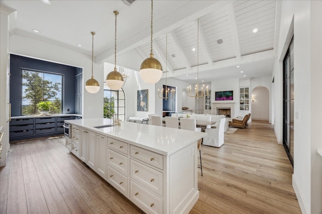 kitchen featuring sink, a breakfast bar area, white cabinetry, pendant lighting, and a kitchen island with sink