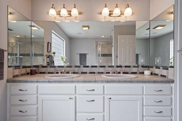 bathroom featuring vanity, a shower with door, and backsplash