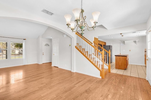 interior space with an inviting chandelier, light hardwood / wood-style flooring, and lofted ceiling