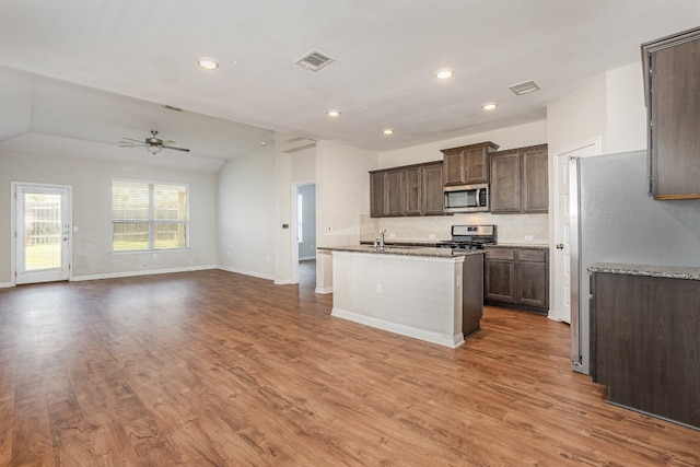 kitchen featuring light hardwood / wood-style flooring, an island with sink, ceiling fan, appliances with stainless steel finishes, and lofted ceiling