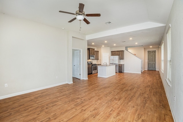 unfurnished living room featuring ceiling fan, sink, and light wood-type flooring