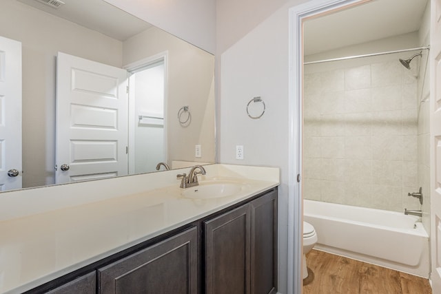 full bathroom featuring vanity, toilet, hardwood / wood-style flooring, and tiled shower / bath