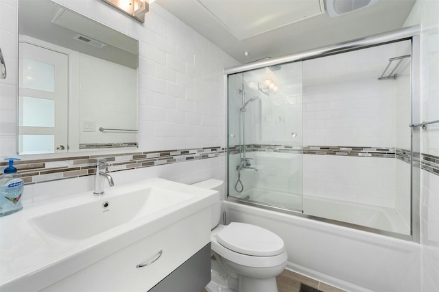 full bathroom featuring toilet, tile walls, bath / shower combo with glass door, tasteful backsplash, and vanity