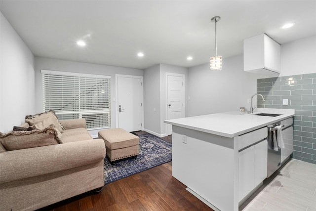 kitchen featuring white cabinetry, decorative light fixtures, sink, hardwood / wood-style flooring, and stainless steel dishwasher