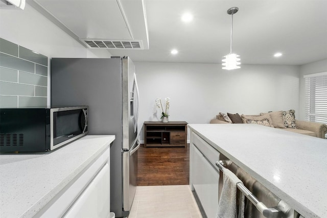 kitchen featuring light wood-type flooring, pendant lighting, light stone counters, and white cabinets