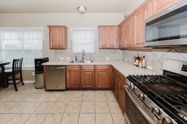 kitchen featuring backsplash, sink, light tile patterned floors, and stainless steel appliances