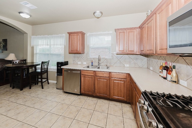 kitchen featuring backsplash, a healthy amount of sunlight, sink, and stainless steel appliances