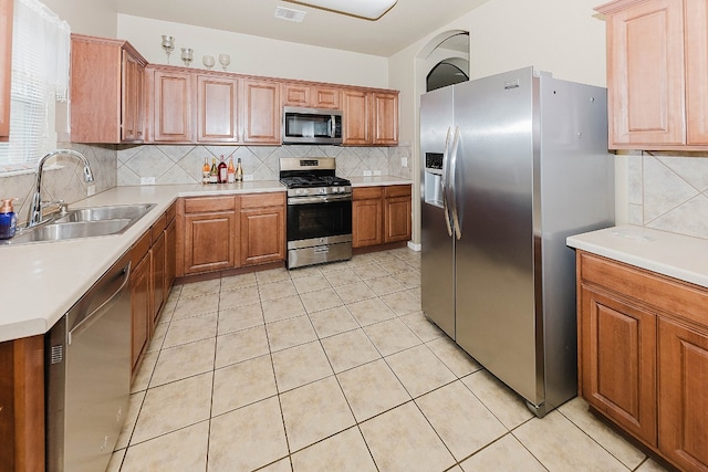 kitchen with light tile patterned floors, backsplash, stainless steel appliances, and sink