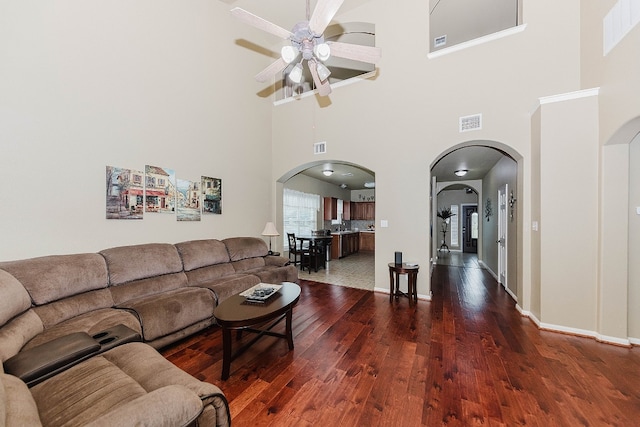 living room with ceiling fan, dark hardwood / wood-style flooring, and a high ceiling