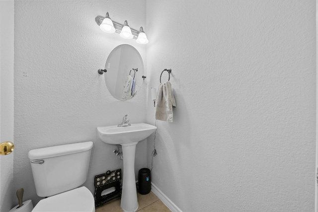 bathroom with toilet, sink, and tile patterned floors