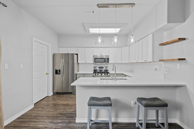 kitchen with white cabinets, appliances with stainless steel finishes, kitchen peninsula, and sink