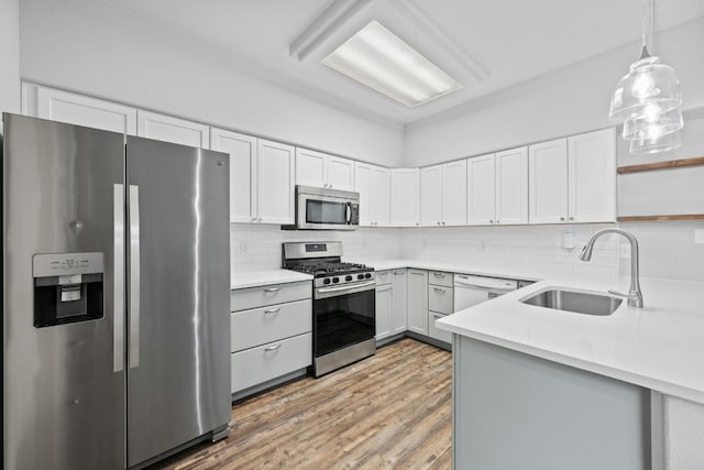 kitchen with tasteful backsplash, stainless steel appliances, sink, white cabinets, and light hardwood / wood-style floors