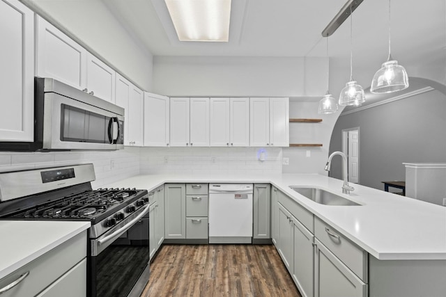 kitchen featuring decorative light fixtures, dark hardwood / wood-style flooring, stainless steel appliances, sink, and kitchen peninsula