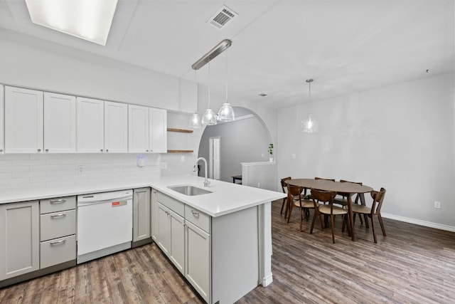 kitchen featuring wood-type flooring, dishwasher, kitchen peninsula, and sink