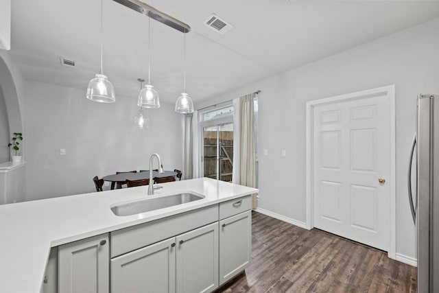 kitchen with gray cabinetry, dark hardwood / wood-style flooring, pendant lighting, stainless steel refrigerator, and sink