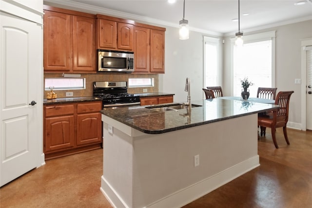 kitchen with concrete flooring, pendant lighting, appliances with stainless steel finishes, a kitchen island with sink, and sink