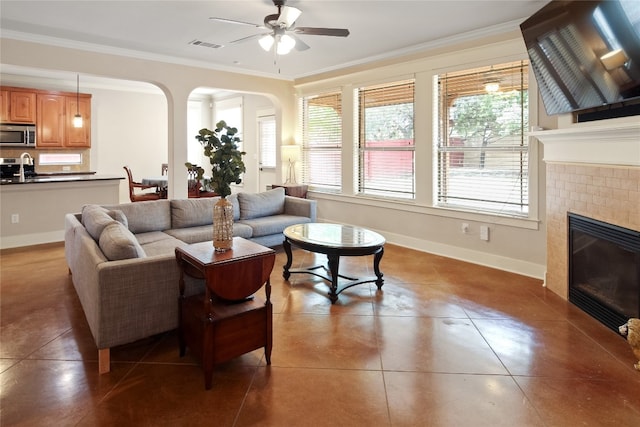 living room with ornamental molding, sink, tile patterned floors, a brick fireplace, and ceiling fan