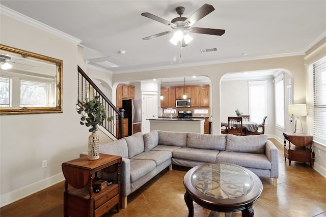 tiled living room with ceiling fan and crown molding