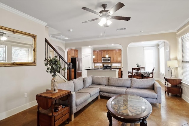 living area with a ceiling fan, visible vents, arched walkways, and crown molding