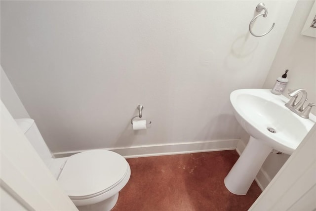 bathroom featuring toilet, baseboards, and a sink