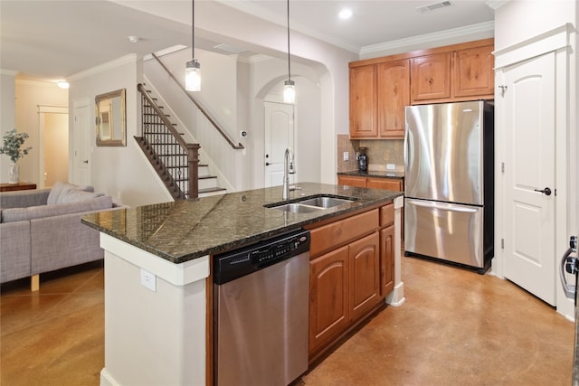 kitchen featuring decorative light fixtures, a center island with sink, appliances with stainless steel finishes, ornamental molding, and sink