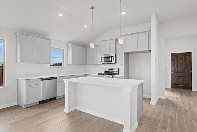 kitchen with stainless steel appliances, vaulted ceiling, sink, pendant lighting, and a center island