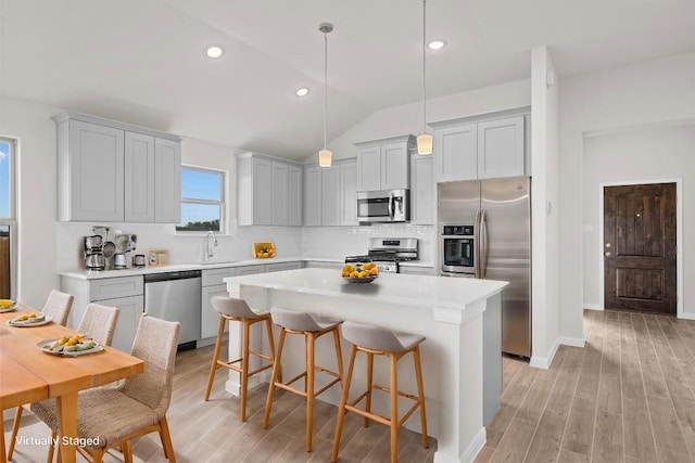 kitchen featuring pendant lighting, stainless steel appliances, a kitchen breakfast bar, tasteful backsplash, and a kitchen island