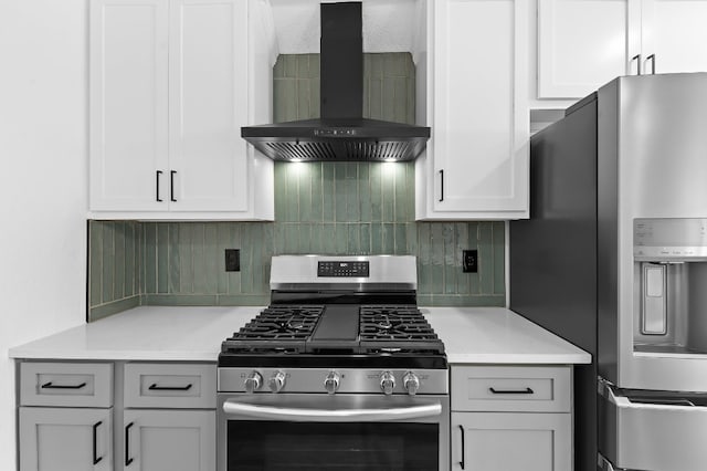 kitchen featuring decorative backsplash, stainless steel appliances, white cabinets, and wall chimney range hood