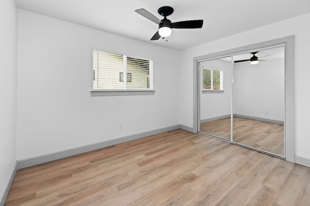 unfurnished bedroom with a closet, light wood-type flooring, multiple windows, and ceiling fan